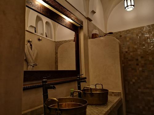 a bathroom with two copper buckets and a mirror at Riad Charme d'Orient Adults Only in Marrakech