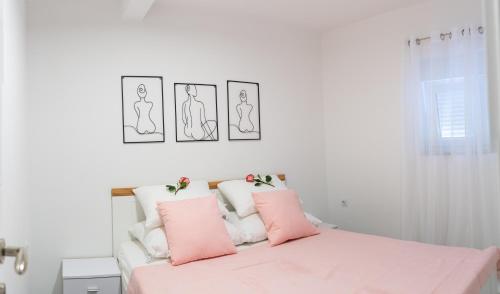 a bedroom with a pink bed with three pictures on the wall at Holiday Home Relax - Mošćenička Draga in Mošćenička Draga
