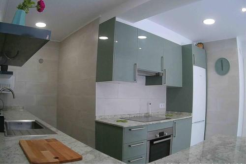 a kitchen with green cabinets and a sink at La Gaviota apartment, in the heart of the port in Jávea
