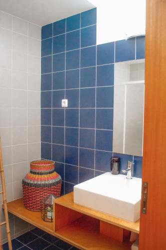 a blue tiled bathroom with a sink and a mirror at Casa da Figueira in Moledo
