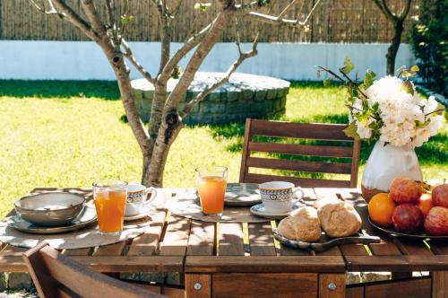 een houten tafel met ontbijtproducten en jus d'orange bij Casa da Figueira in Moledo