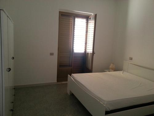 a white bedroom with a bed and a window at Appartamento sul Mare Capo Rizzuto in Capo Rizzuto