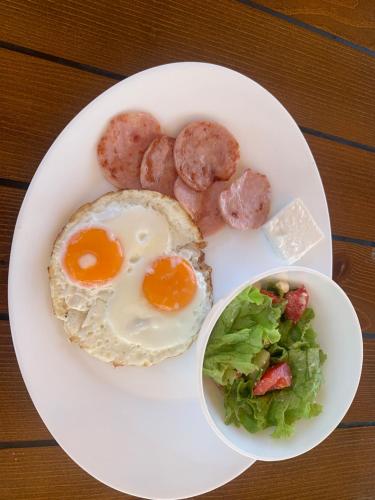 a plate of breakfast food with eggs sausage and salad at Resort Bevilacqua in Budva