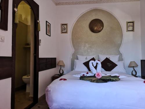 a bedroom with a white bed with a flower on it at Riad Charme d'Orient Adults Only in Marrakech