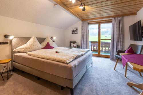a bedroom with a large bed and a balcony at Landhaus Berktold in Obermaiselstein