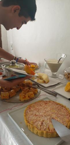 a man is looking at a table with a pizza at Pousada Varanda do Sol in Arraial d'Ajuda