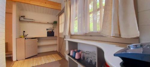 Elle comprend une petite cuisine avec un évier et une fenêtre. dans l'établissement Kempings Saulkrastos, à Saulkrasti