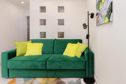 a green couch in a living room with yellow pillows at Apartament Zielony Sopot Karlikowo by Renters in Sopot