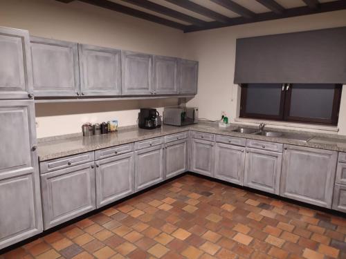 uma grande cozinha com armários cinzentos e um lavatório em Surrender three bedrooms em Aan de Wolfsberg