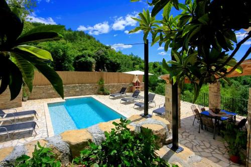 a pool in a garden with chairs and a table at Villa Alba in Livade