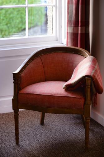a red couch sitting in front of a window at THE Waterloo Arms Hotel in Chirnside