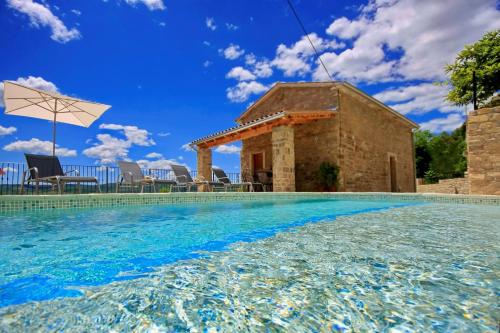 a swimming pool with a house and an umbrella at Villa Alba in Livade