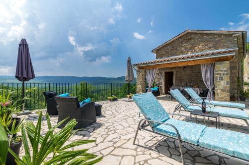 a patio with blue chairs and an umbrella at Villa Alba in Livade