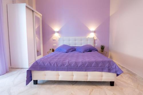 a purple bedroom with a bed with purple sheets and pillows at ΒΟΛΤΑ στουντιο στην καρδιά της Πρεβεζας in Preveza
