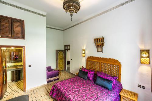 a bedroom with a large bed with purple sheets at Riad Jardin Chrifa in Fès