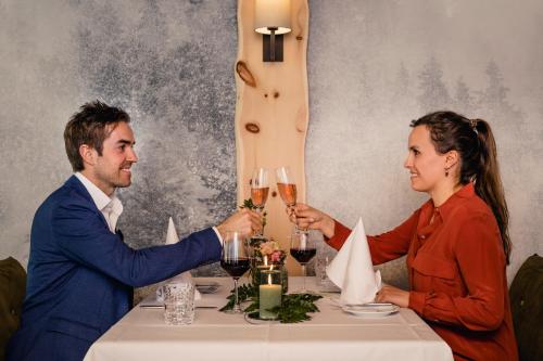 a man and woman sitting at a table with glasses of wine at Hotel Gasthof Ochsen in Kißlegg