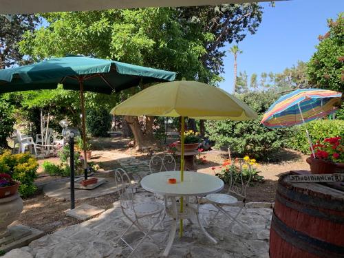a table with two umbrellas and a table with chairs at Villa Anna GuestHouse in Brindisi
