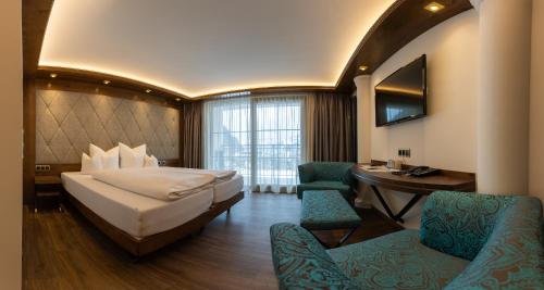 Habitación de hotel con cama, escritorio y sillas en Strass - Sport & Spa Hotel en Mayrhofen
