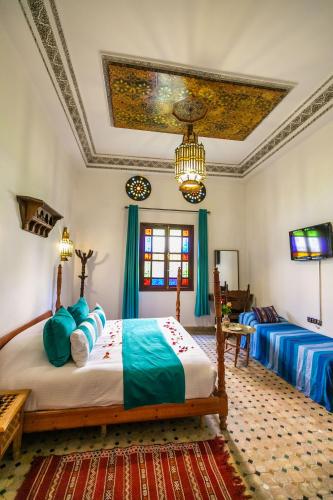 a bedroom with two beds and a tv in it at Riad Jardin Chrifa in Fès