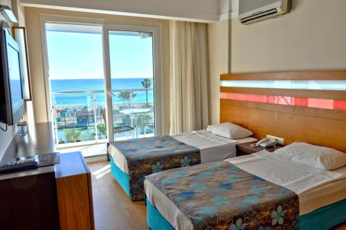 a hotel room with two beds and a large window at Sultan Sipahi Resort Hotel in Alanya