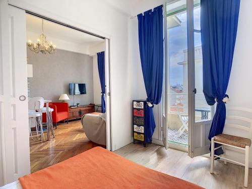 Cet appartement comprend une chambre avec des rideaux bleus et une chambre avec un balcon. dans l'établissement Nestor&Jeeves - HAPPINESS BEACH - Central - Close sea - Top floor, à Nice