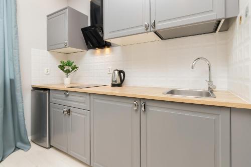 a kitchen with white cabinets and a sink at Apartments Gdynia Abrahama in Gdynia
