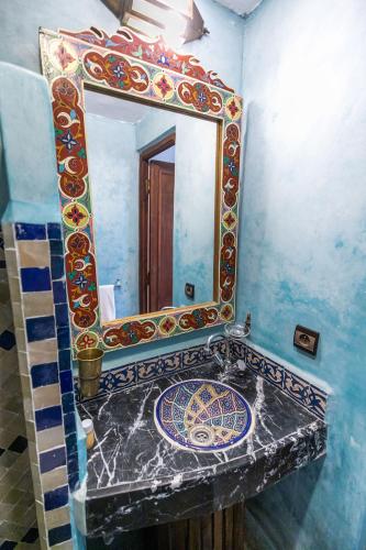 a bathroom with a mosaic sink and a mirror at Riad Jardin Chrifa in Fès