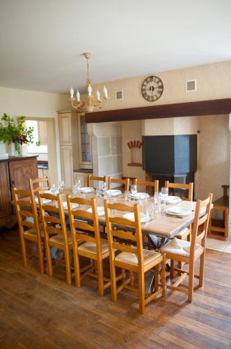 a dining room with a table with chairs and a clock at La Ferme du Cayla in Linac
