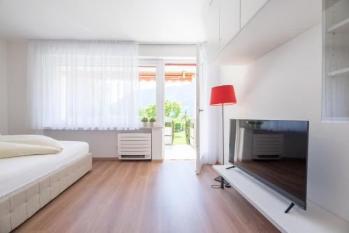 a white bedroom with a bed and a television at Fior Apartments Pienzenau in Merano