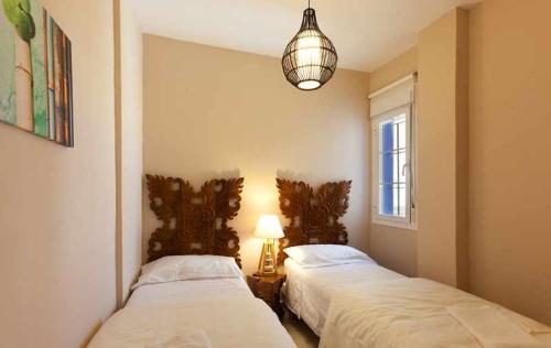 タリファにあるTarifa Beach Rentals Tortuga 2のベッド2台、ベッドルーム(ランプ、窓付)