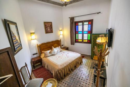 a bedroom with a bed and a stained glass window at Riad Jardin Chrifa in Fès