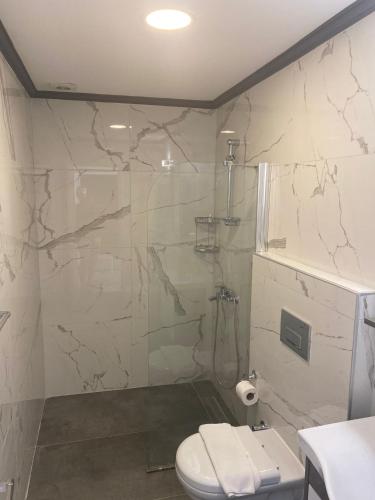 a bathroom with a toilet and a glass shower at Nur Suites & Hotels in Kalkan
