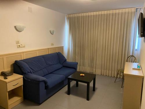 a living room with a blue couch and a table at Hotel Cogullada in Zaragoza