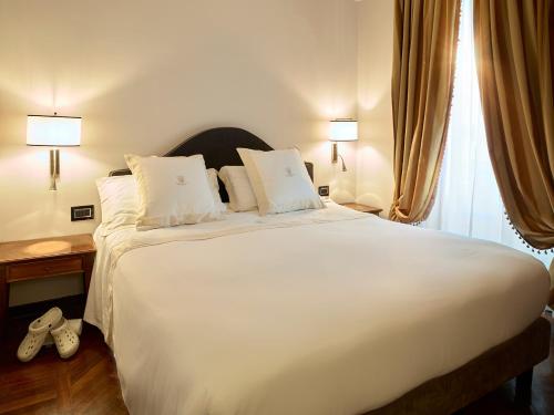 a bedroom with a large white bed with two lamps at Hotel Niccolo' V - Terme dei Papi in Viterbo