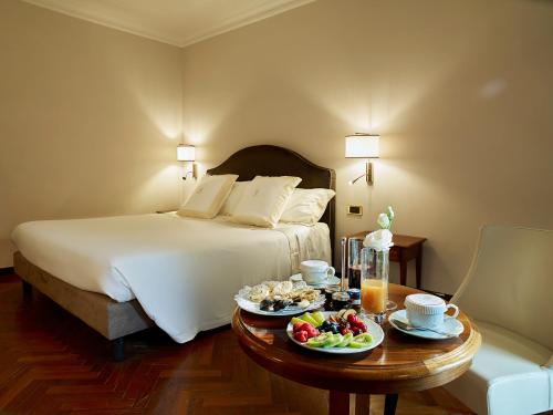 a hotel room with a bed and a table with food on it at Hotel Niccolo' V - Terme dei Papi in Viterbo