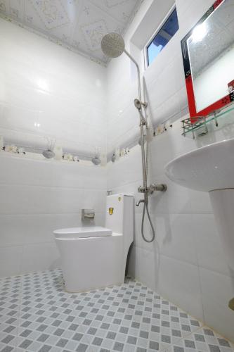 a white bathroom with a toilet and a sink at Windy Villa Vung Tau in Vung Tau