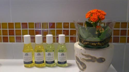 three bottles of essential oils and a vase with flowers at Hotel Boutique Las Arenas in Es Cana