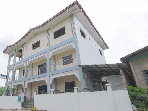 a white building with a fence in front of it at OYO 781 Junie Pension House in Moalboal