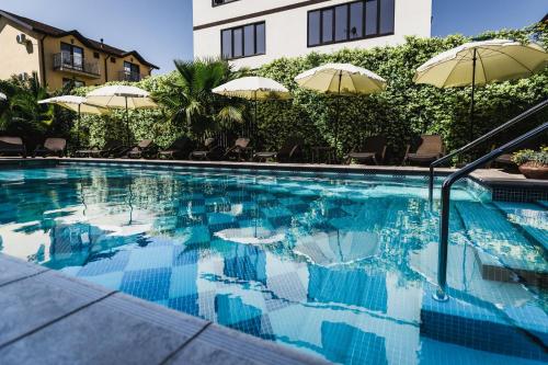 a swimming pool with umbrellas and a building at Hotel Soprano in Adler