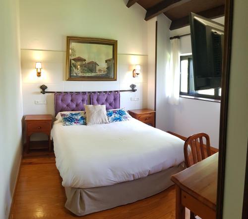 a bedroom with a large bed with a purple headboard at Amaicha Hotel Rural in Ribadesella