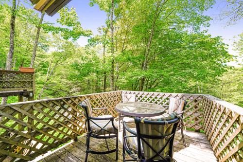 a table and two chairs on a deck with trees at The Hemlock Hideaway in Sugar Mountain