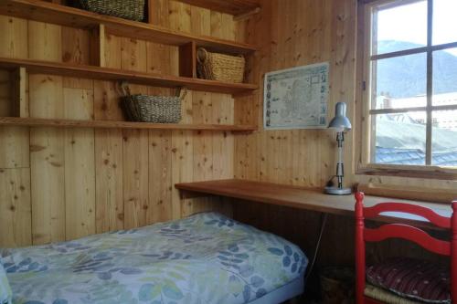 a bedroom with a wooden wall with a desk and a bed at Maison traditionnelle briançonnaise in Briançon