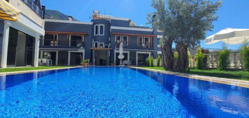 a large blue swimming pool in front of a house at Nur Suites & Hotels in Kalkan
