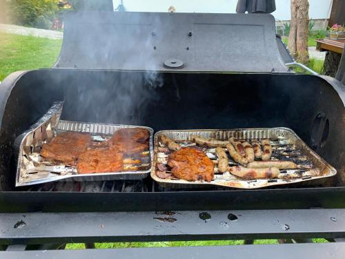 two pans of meat and sausages on a grill at Mezná 85 in Hřensko