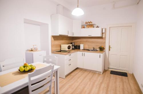 una cucina con armadi bianchi e un tavolo con frutta di Central House Morariu a Sibiu
