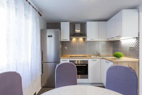 a kitchen with purple chairs and a white refrigerator at Apartments Lidija - sea view apartment with exclusive right of using hot tub or split level apartment with exclusive right of using pool in Podstrana
