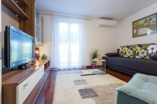 a living room with a tv and a couch at Apartments Lidija - sea view apartment with exclusive right of using hot tub or split level apartment with exclusive right of using pool in Podstrana