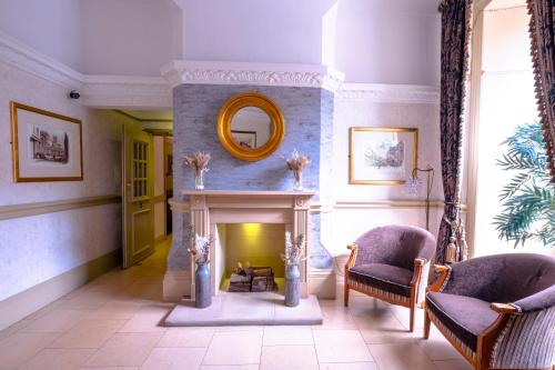 a living room with a fireplace and two chairs at Royal Hotel in Bath