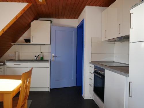 uma cozinha com armários brancos e uma porta azul em Haus Josefine em Friedrichshafen