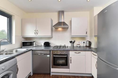 a kitchen with white cabinets and a stove top oven at Bright 2 Bedroom Flat in Lambeth With Balcony in London